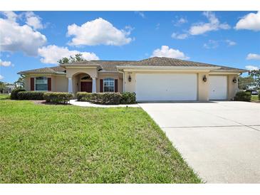 Beautifully landscaped single-story home with a three car garage and a well-manicured front lawn at 12012 Cromwell Way, Spring Hill, FL 34609