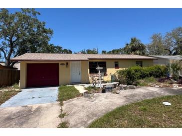 Charming single-story home with mature trees, a red garage door, and a well-lit entrance at 12049 132Nd Ave, Seminole, FL 33778