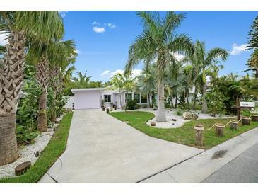 Charming single-story home with tropical landscaping and a spacious driveway leading to an attached garage at 1210 Bay Palm Blvd, Indian Rocks Beach, FL 33785