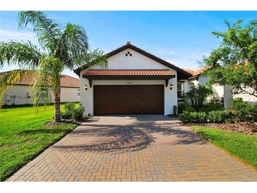 Charming home featuring a tile roof, brick driveway, and lush landscaping, creating great curb appeal at 16913 Anchor Root St, Wimauma, FL 33598