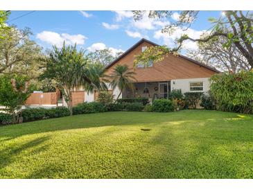 Charming home featuring lush landscaping, a well-manicured lawn, and a unique wood exterior at 1799 Dixie Hwy, Tarpon Springs, FL 34689
