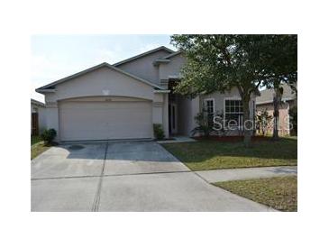 Two-story house with a beige exterior, attached two-car garage, and well-maintained lawn at 30742 Birdhouse Dr, Wesley Chapel, FL 33545