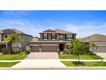 Inviting two-story home with a well-manicured lawn, paver driveway, and a two-car garage at 4917 Eagle Rock Dr, Wimauma, FL 33598