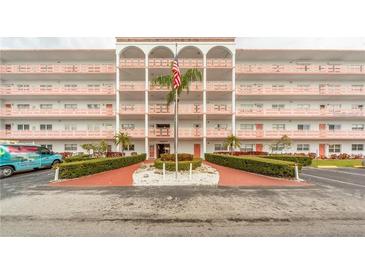 Multi-story condominium building featuring a central entrance with an American flag and well-maintained landscaping at 5501 80Th N St # 207, St Petersburg, FL 33709
