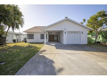 Charming single-story home with a well-maintained lawn, attached garage, and covered entrance at 811 Bay Point Dr, Madeira Beach, FL 33708