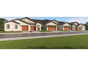 Row of modern townhomes with tan exteriors, dark roofs and a well-manicured lawn at 10873 Rustic Eve Ct, Land O Lakes, FL 34638