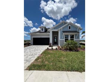 Charming single-story home with blue siding, a well-manicured lawn, and a paved driveway at 1599 Running Tide Pl, Sarasota, FL 34240