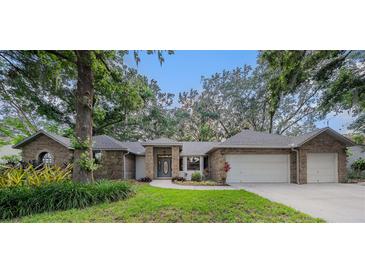 Charming brick home with a well-manicured lawn, mature trees, and a two-car garage at 2838 Timber Knoll Dr, Valrico, FL 33596