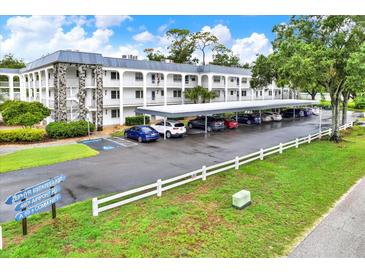 Beautiful condo building featuring private balconies, covered parking, and lush landscaping at 4801 Airport Rd # 210, Zephyrhills, FL 33542