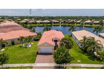 Waterfront home with a red tile roof, beautiful landscaping, and a spacious lawn at 4821 Grand Banks Dr, Wimauma, FL 33598