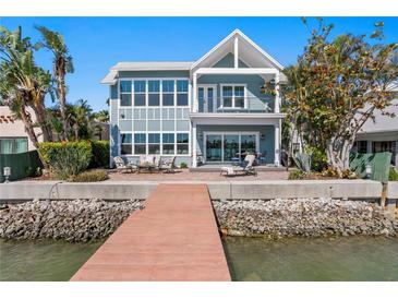 Waterfront home featuring a patio with outdoor seating, a private dock, and direct water access on a sunny day at 2903 Pass A Grille Way, St Pete Beach, FL 33706