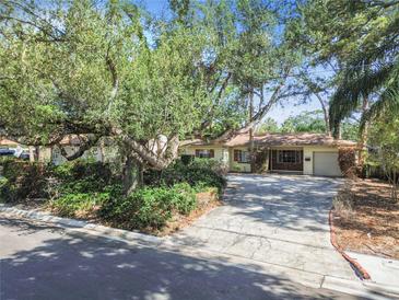 Charming single-story home featuring a long driveway and lush landscaping, including mature trees offering shade at 4711 W Vasconia St, Tampa, FL 33629