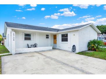 Charming single-story home featuring a covered front porch and a well-maintained concrete driveway and white facade at 8708 Albion Ct, Tampa, FL 33634