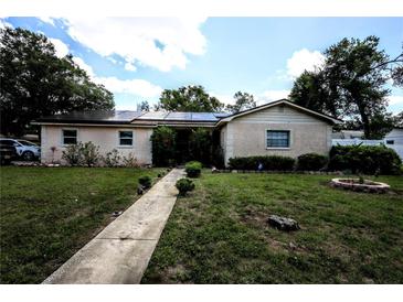 Charming single-story home featuring solar panels, a well-maintained lawn, and a welcoming walkway at 11411 N 19Th St, Tampa, FL 33612