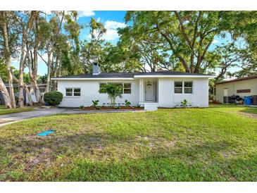 Charming single-story home featuring a manicured lawn and fresh landscaping, painted in white at 1352 Parkwood St, Clearwater, FL 33755