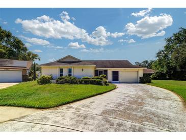 Well-maintained home with lush landscaping and a paved driveway leading to the garage at 3053 Gregor Ct, Palm Harbor, FL 34684