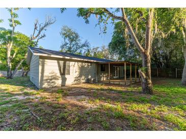 The backyard features a covered patio perfect for outdoor entertaining, surrounded by mature trees and lush greenery at 9834 Miramar St, New Port Richey, FL 34654