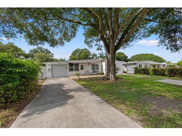 Charming single-story home featuring mature landscaping, a driveway, and an attached garage at 1035 58Th N Ave, St Petersburg, FL 33703