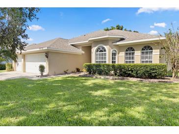 Tan home featuring arched windows and manicured shrubs set on a bright green lawn at 3023 Minuteman Ln, Brandon, FL 33511