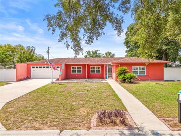 Charming one-story home featuring a manicured lawn, attached garage, and vibrant coral exterior paint at 603 Royal Crest Dr, Brandon, FL 33511