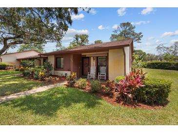 Charming single-story home featuring a well-maintained lawn, mature landscaping and inviting front porch with rocking chairs at 7535 Greystone Dr, Hudson, FL 34667