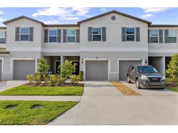 Charming townhouse featuring a two-car garage, landscaped front yard, and neutral color palette at 10472 Shady Preserve Dr, Riverview, FL 33578