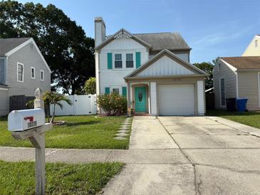 Charming two-story home featuring a well-maintained lawn, white picket fence, and colorful turquoise accents at 10775 Glen Ellen Dr, Tampa, FL 33624