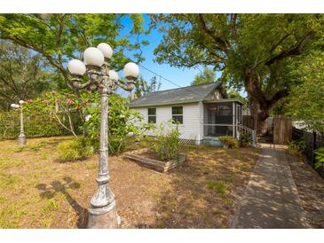 Charming cottage-style home featuring mature trees, lush landscaping and a screened in porch at 1216 E Lambright St, Tampa, FL 33604