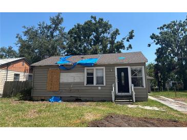 Exterior view of a quaint home needing repairs, featuring a covered roof and front lawn at 2011 Oakwood Ave, Tampa, FL 33605