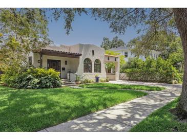 Charming home featuring a stucco exterior, arched windows, tile roof, and lush landscaping on a sunny day at 2511 W Morrison Ave, Tampa, FL 33629