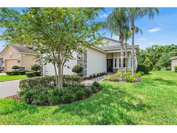 Beautifully landscaped single-story home with stone accents and a well-manicured lawn at 30410 Ceasar Park Dr, Wesley Chapel, FL 33543