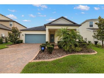 Charming single-story home featuring a brick driveway, a blue garage door, and meticulously landscaped front yard at 3972 Wisdom Trl, Land O Lakes, FL 34638