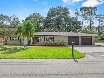 Charming single-story home with a well-manicured lawn, complemented by mature trees and a double car garage at 7137 Wedgewood Dr, New Port Richey, FL 34652