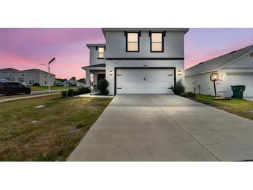 Contemporary two-story home with a long driveway and an attached two-car garage at 7380 Sail Clover Ln, Zephyrhills, FL 33540