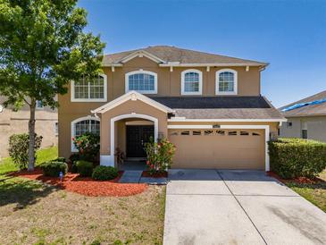 Inviting two-story home featuring a well-manicured lawn, mature trees, and an attached two-car garage at 7852 Stoney Hill Dr, Wesley Chapel, FL 33545