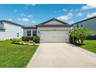 Charming single-story home featuring a manicured lawn, complemented by a 2-car garage and a classic gray exterior at 8496 Starlight Loop, Parrish, FL 34219