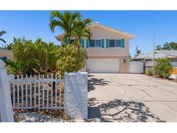 Charming two-story home with blue shutters, a white picket fence, and a spacious driveway at 1210 Bay Pine Blvd, Indian Rocks Beach, FL 33785