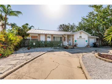 Charming single-story home featuring a metal roof, white exterior with decorative accents, and a well-manicured front yard at 1857 Bayou Grande Ne Blvd, St Petersburg, FL 33703