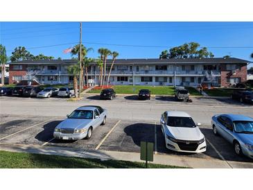 Two-story condo complex featuring a mix of car parking and tropical palm trees against a blue sky backdrop at 2353 Shelley St # 6, Clearwater, FL 33765