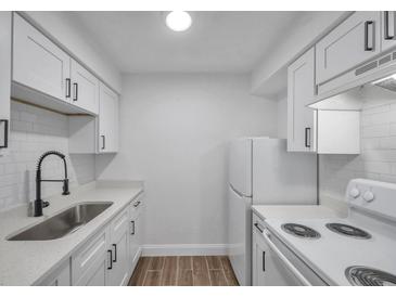 Bright kitchen features white cabinets, subway tile backsplash, modern countertops, and stainless steel sink at 2353 Shelley St # 6, Clearwater, FL 33765