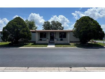 Charming home featuring a covered front porch, complemented by lush landscaping and mature trees at 34300 Countryside Dr, Wesley Chapel, FL 33543