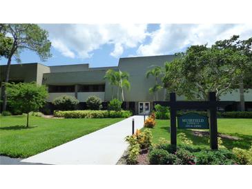 Well maintained condo building with lush lawn, mature landscaping, and decorative sign at 36750 Us 19 N # 15309, Palm Harbor, FL 34684