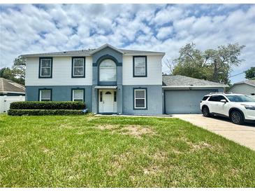 Inviting two-story home featuring a well-manicured lawn and attached two car garage at 3181 Deltona Blvd, Spring Hill, FL 34606