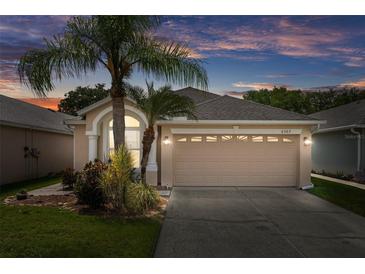 Charming single-story home featuring an attached two-car garage and lush landscaping, captured at twilight at 6303 Gentle Ben Cir, Wesley Chapel, FL 33544