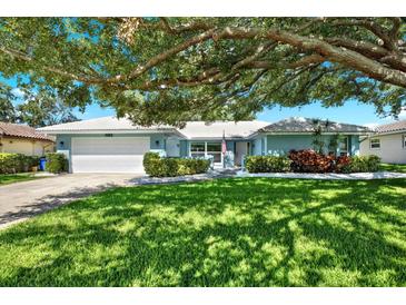 Charming single-story home with a manicured lawn, lush landscaping, and inviting curb appeal under a large tree at 7092 119Th St, Seminole, FL 33772