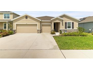 Inviting home featuring a 3-car garage, stone accents, manicured lawn, and a welcoming entrance at 12401 Shining Willow St, Riverview, FL 33579