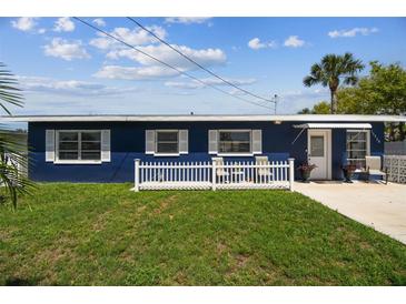 Charming blue single-story home featuring a well-manicured lawn and a cozy front patio with white picket fence at 13920 Berkowitz Ave, Hudson, FL 34667