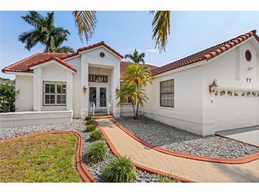 Charming home featuring lush landscaping, a red tile roof, and a welcoming entrance at 77 Gulfwinds Dr, Palm Harbor, FL 34683