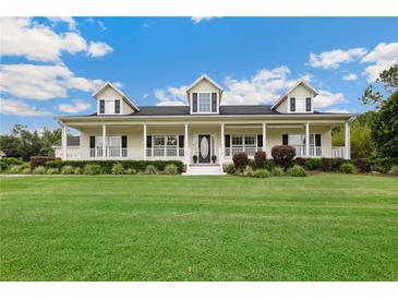 Charming home with a large front porch, manicured lawn and beautiful landscaping at 9830 Caribou Trl, Dade City, FL 33525