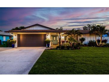 Charming home with a well-manicured lawn and tropical landscaping, illuminated by warm exterior lighting at 13168 84Th Ter, Seminole, FL 33776